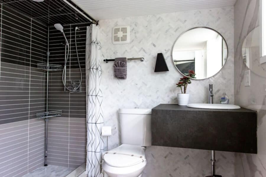 Modern tiny house bathroom with shower, mirror, and minimalist decor.