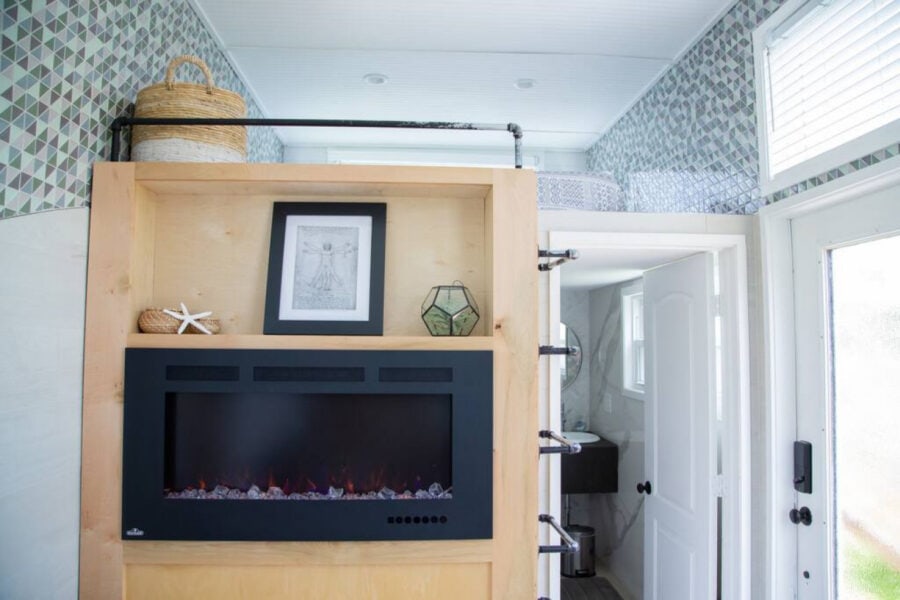 Cozy tiny house interior with modern fireplace and bright natural light.