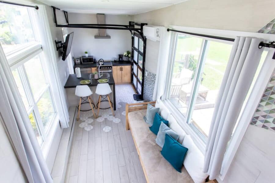 Cozy tiny house interior with large lakefront windows and modern decor.