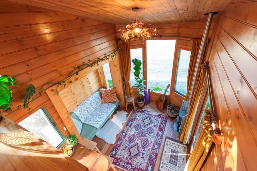 Bright tiny house interior with wooden walls and large windows.