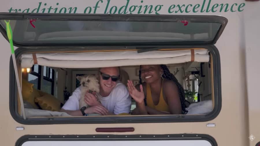 Happy couple inside their tiny bus conversion, showcasing small space living.