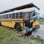 Dreamy 40-foot blue bus converted into a tiny home with solar panels and outdoor living space.