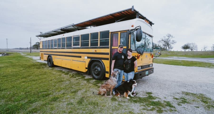 Dreamy 40-foot blue bus converted into a tiny home with solar panels and outdoor living space.