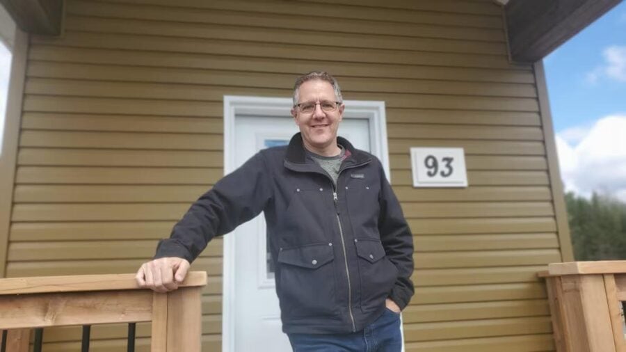 Affordable tiny house with a man standing outside, showcasing small space living.