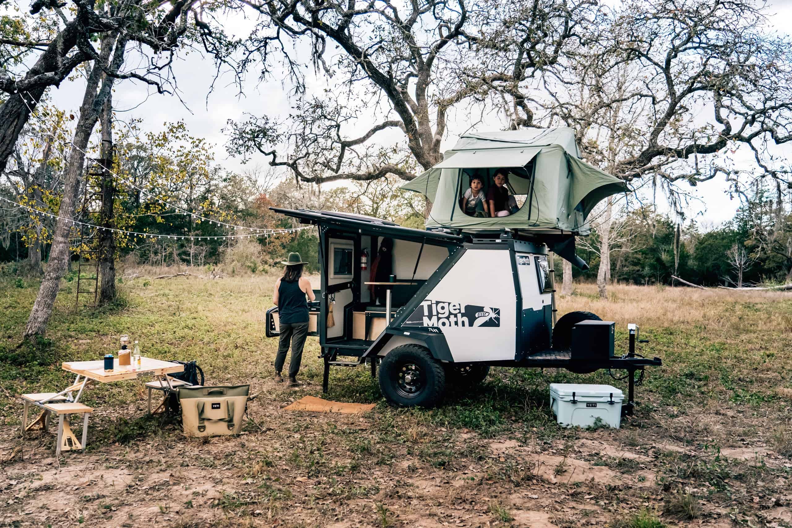 Mobile tiny house with rooftop sleeping area and outdoor living space.