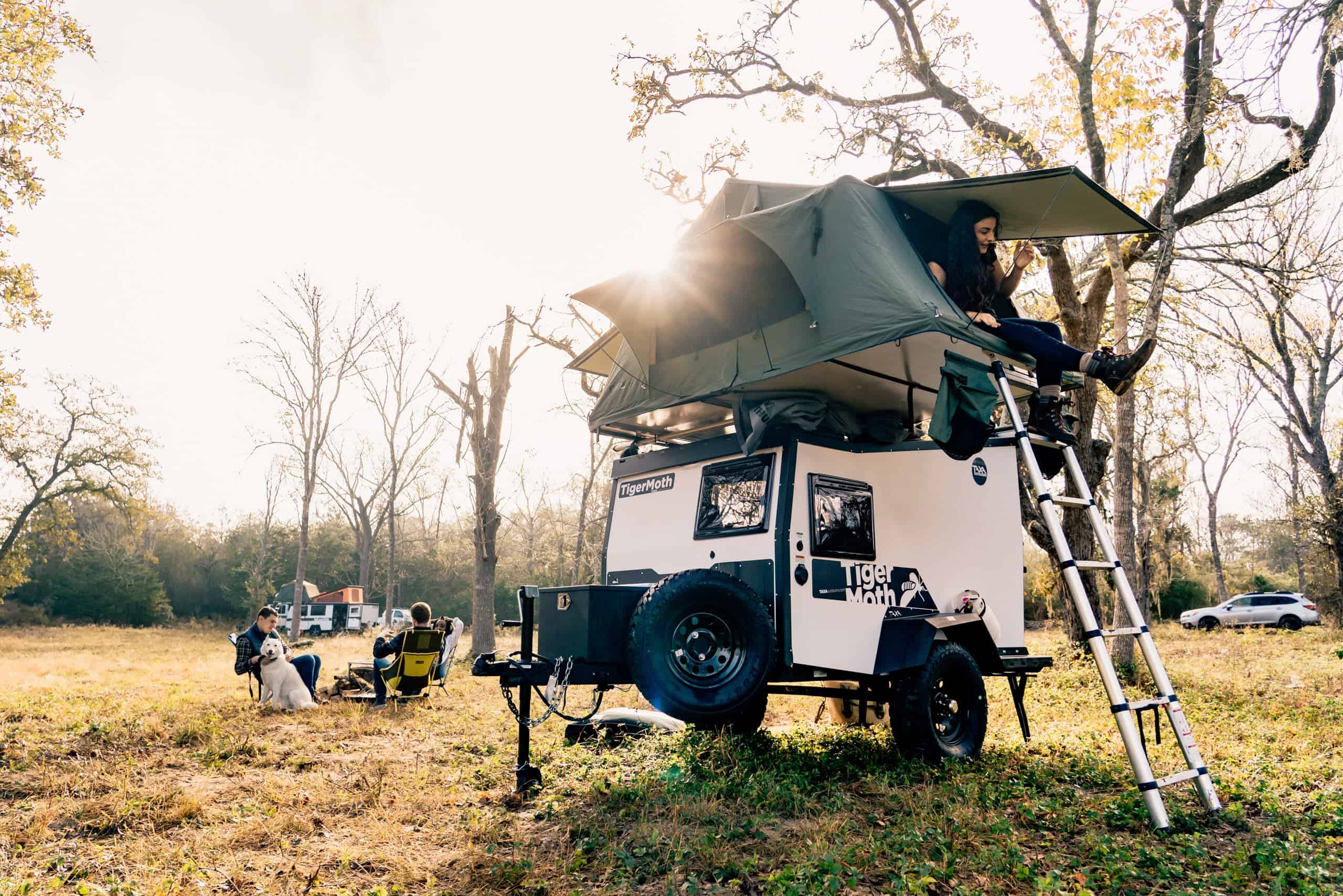 Rooftop tent setup on a compact tiny house trailer in a scenic outdoor setting.