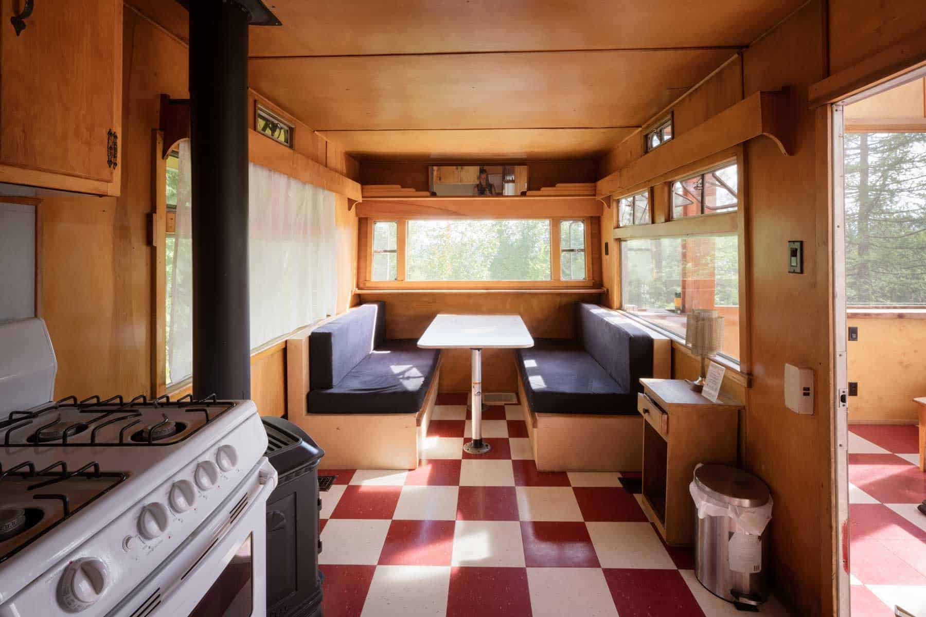 The dinette inside Tin Poppy Cabin that converts to a queen bed, with original crank-out trailer windows