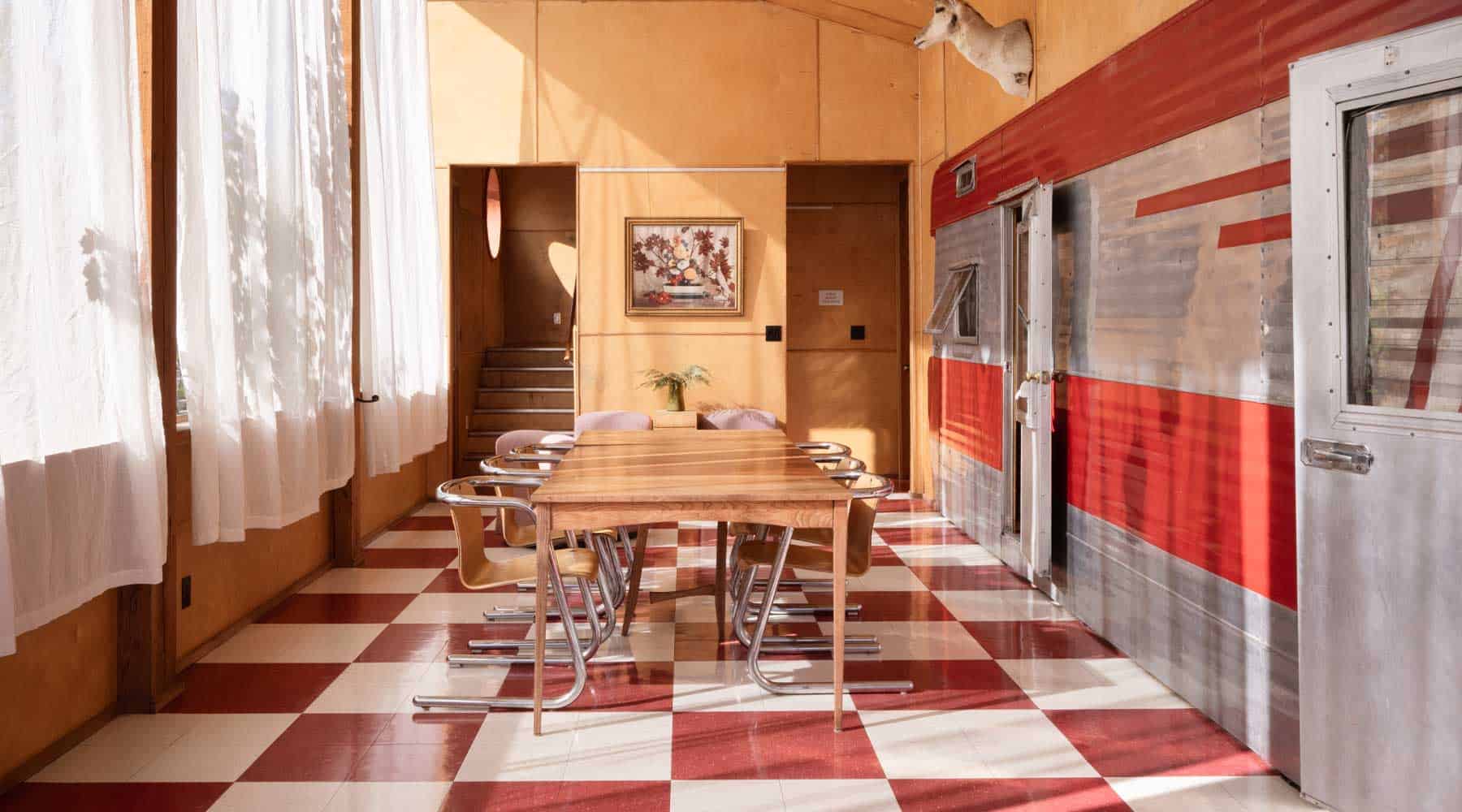 The screened living and dining area at Tin Poppy Cabin, with checkerboard floor and the vintage trailer door