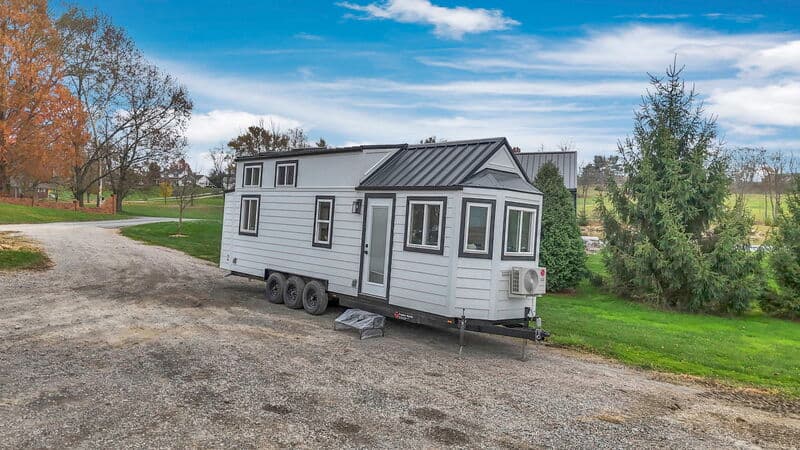 Portable tiny house on wheels with modern design and large windows.