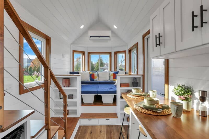 Tiny house interior with large windows and cozy sleeping nook.