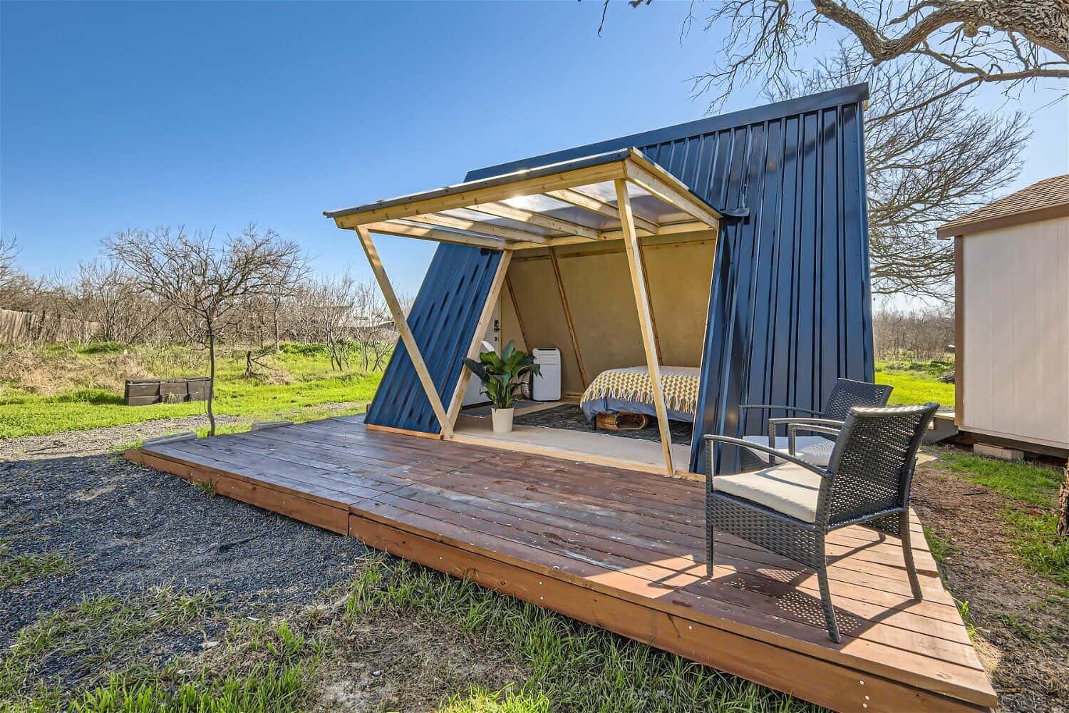 Side view of tiny A-frame cabin near Austin showing blue metal cladding deck and seating area