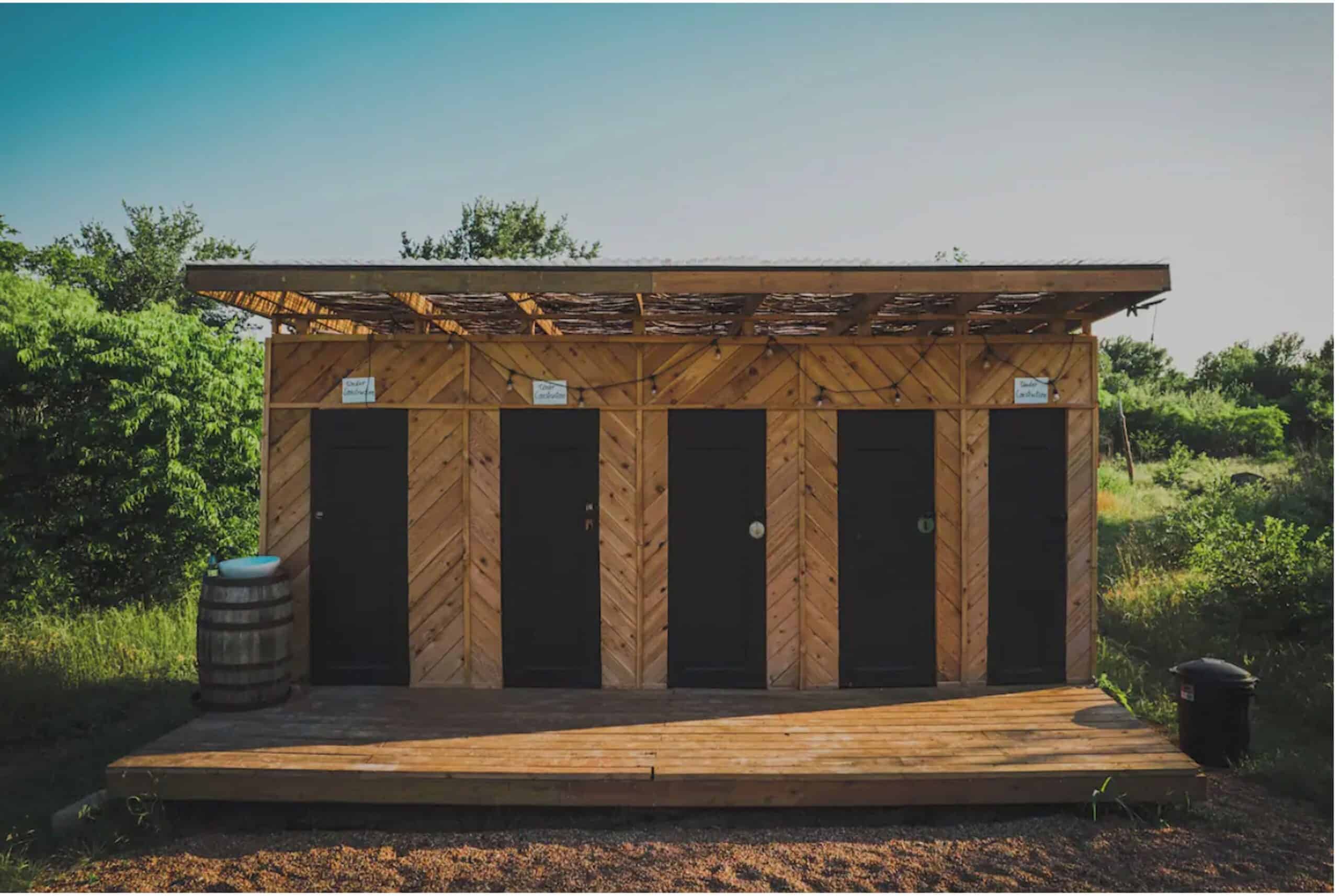 Cedar bathhouse with herringbone wood pattern, black doors, and string lights at A-frame property
