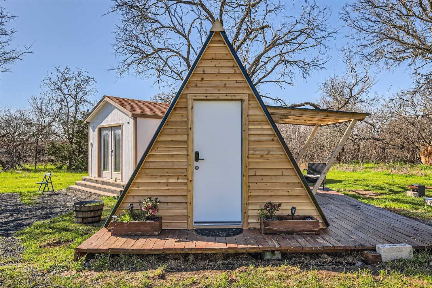 Front view of the tiny A-frame cabin with white door and wood deck on 5 acres near Austin