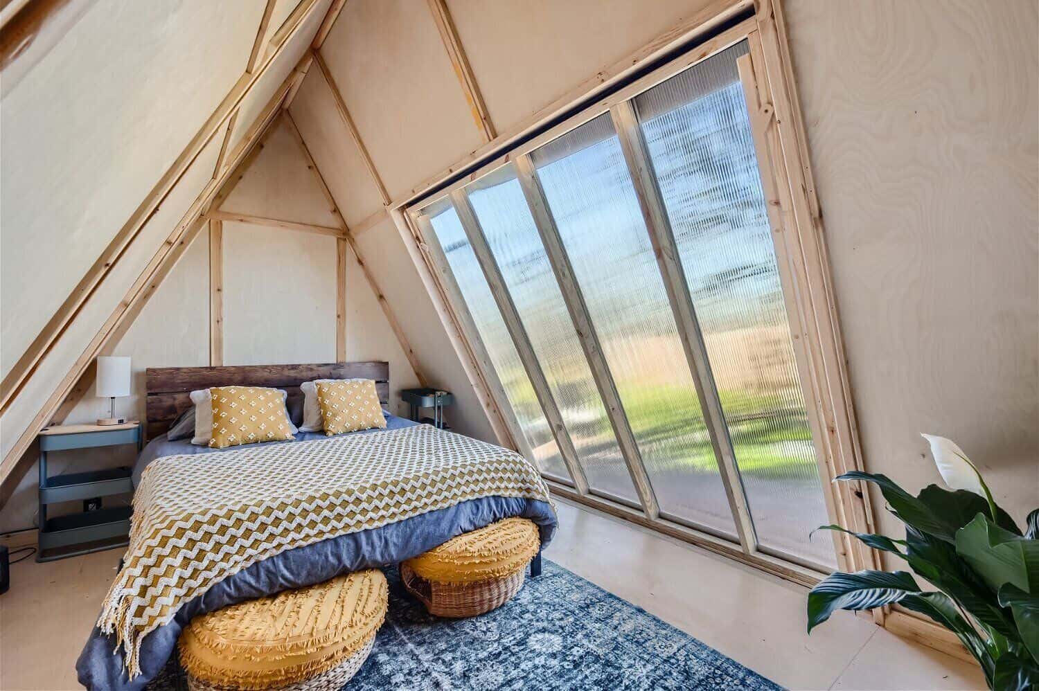 Inside the tiny A-frame cabin near Austin Texas with queen bed, boho textiles, and A-frame ceiling