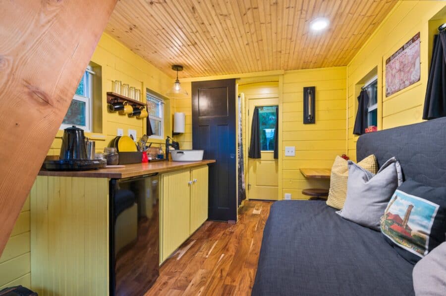 Long narrow interior of the Arthur train car tiny house at Tiny Digs with kitchen and couch