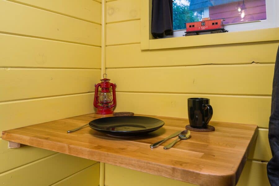 Fold-down table with red lantern and toy caboose in the Arthur tiny house