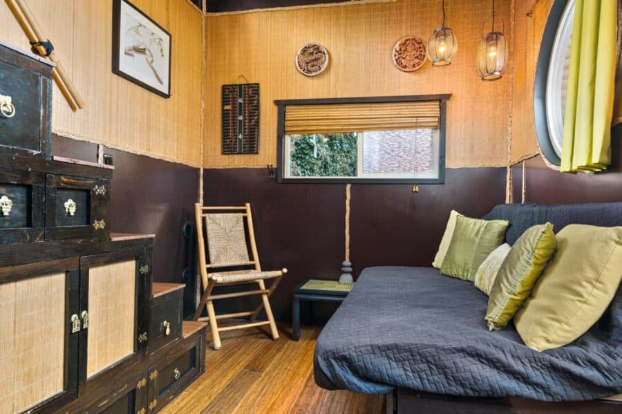 Living room with couch bed, bamboo chair, and grass cloth walls in the Bamboo tiny house