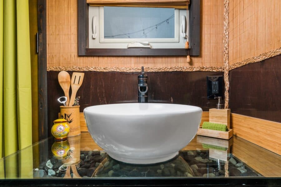 White vessel sink floating over black river rock and jade stones in the Bamboo tiny house