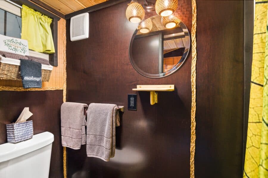 Bathroom with round mirror and bamboo accents in the Bamboo tiny house