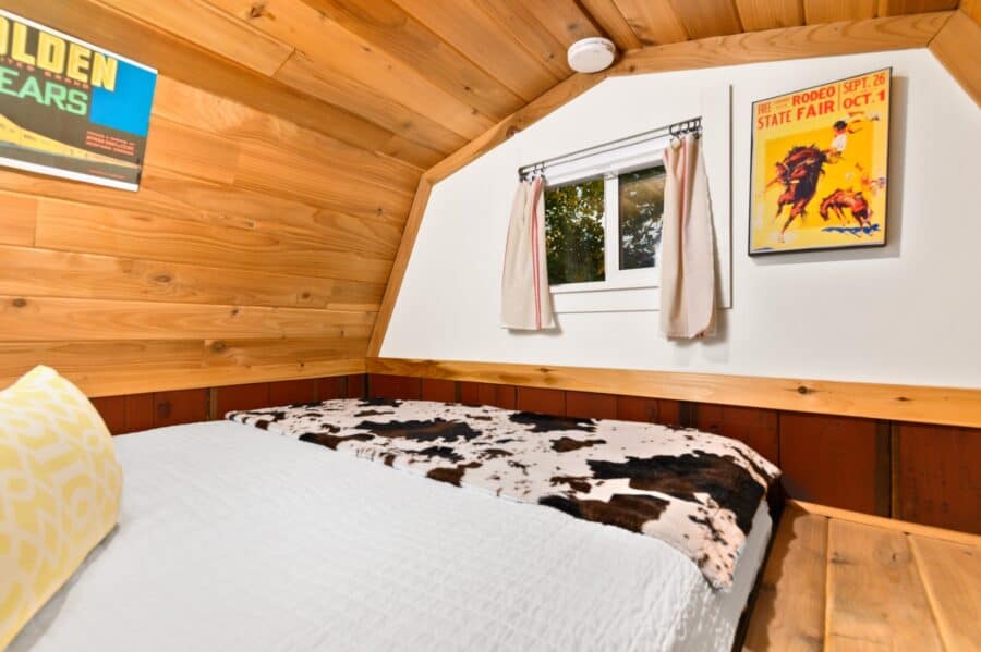 Sleeping loft with cowhide throw inside the Barn tiny house at Tiny Digs