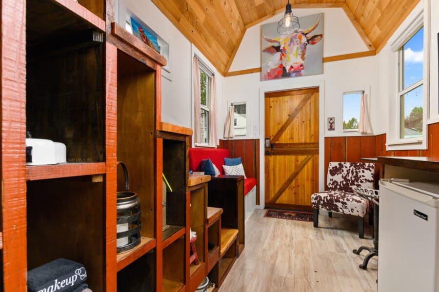 Storage cubbies under the stairs and view to the Dutch door in the Barn tiny house