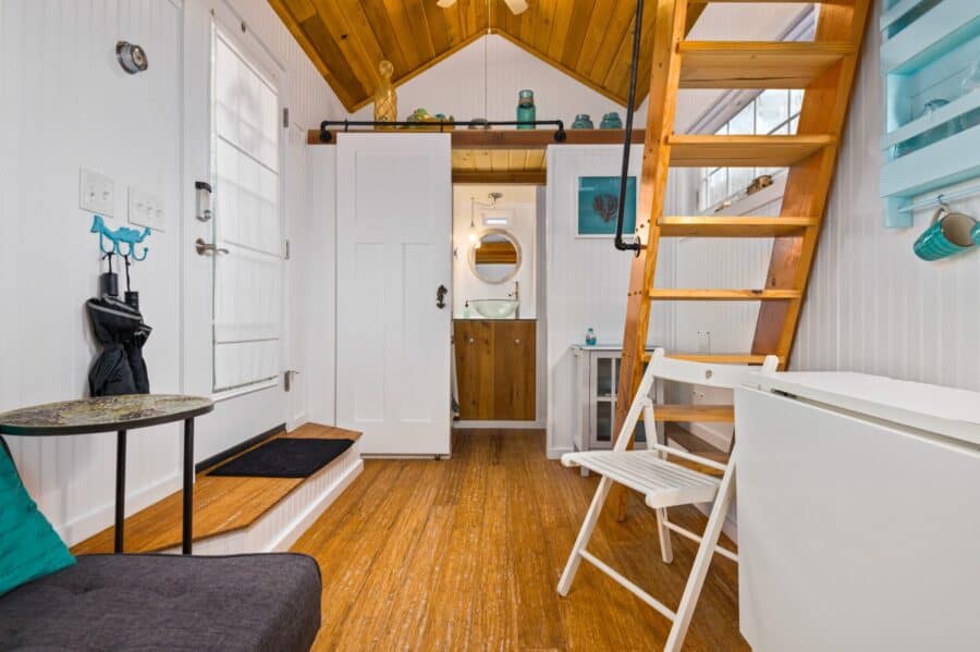 White interior of the Beach tiny house with turquoise accents and wide loft ladder