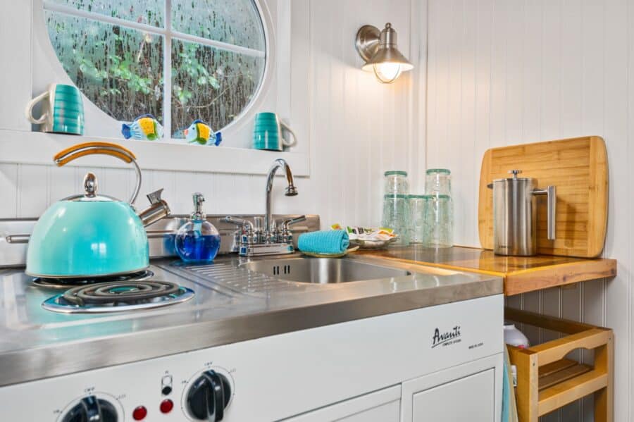 Kitchenette with turquoise kettle and round window in the Beach tiny house at Tiny Digs