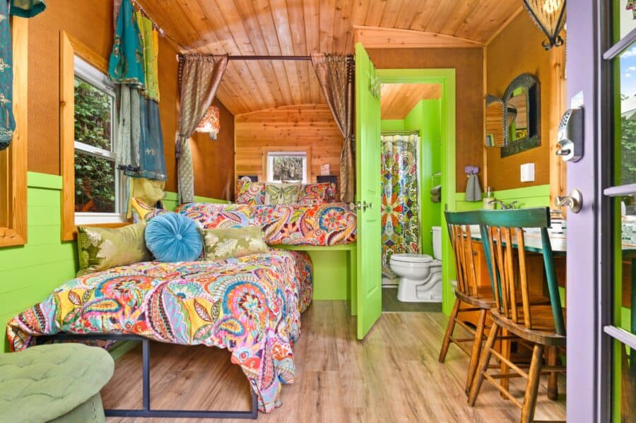 Canopied queen bed with paisley quilt on the main floor of the Boho Wagon tiny house