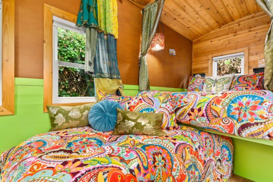 Paisley quilt and pillows on the canopied bed in the Boho Wagon tiny house