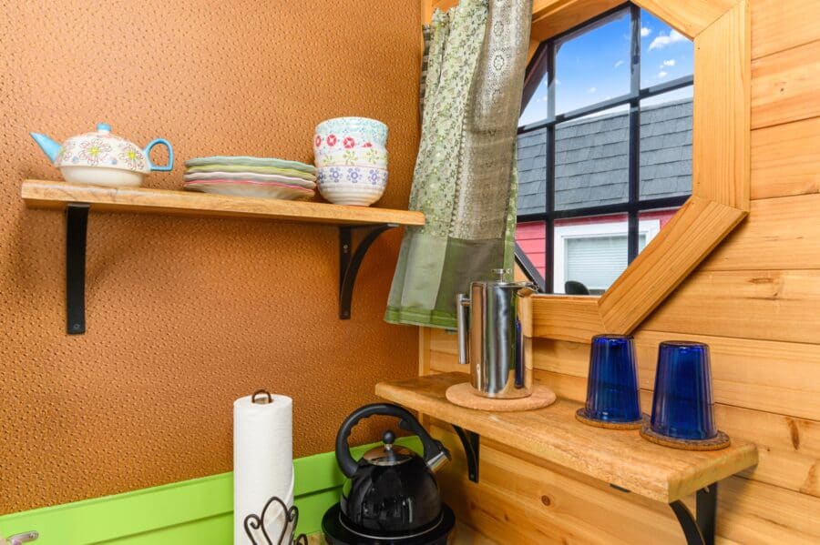 Wood shelves with teapot and blue glasses under an octagon window in the Boho Wagon