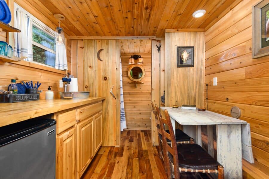 Cedar-paneled interior and crescent moon bathroom door in the Cabin tiny house