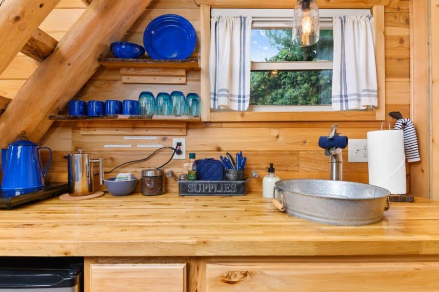 Kitchenette with live-edge shelves and galvanized basin in the Cabin tiny house