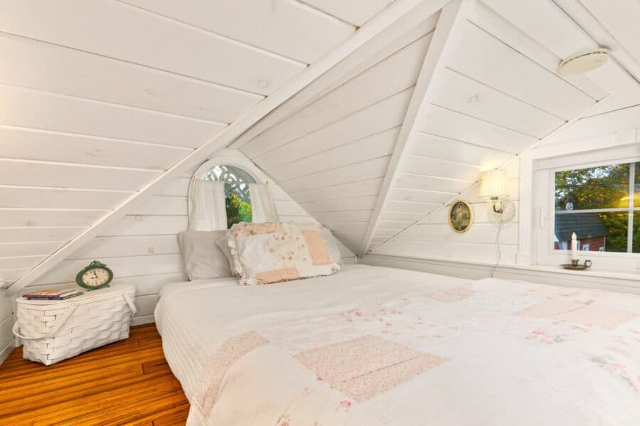 Queen bed with patchwork quilt in the sleeping loft of the Cottage tiny house
