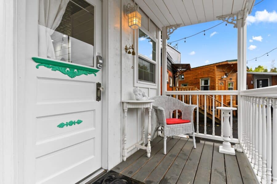 Covered front porch with wicker chair at the Cottage tiny house at Tiny Digs