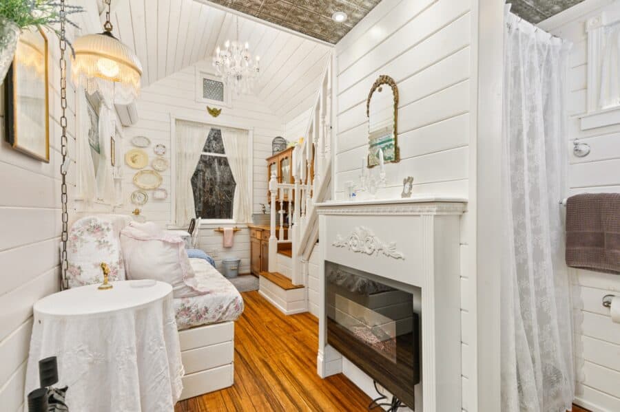 Chandelier, table, and white fireplace inside the Cottage tiny house at Tiny Digs