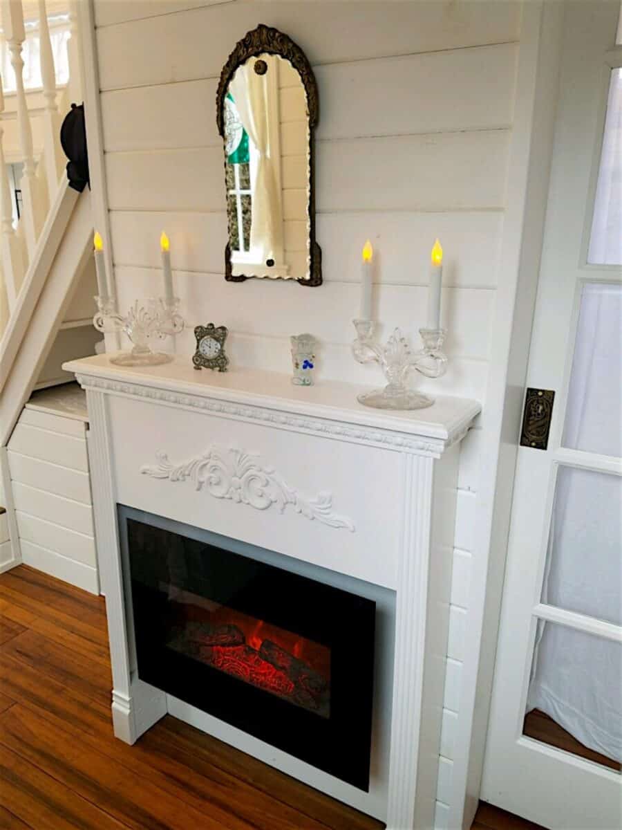 Carved white mantel and electric fireplace in the Cottage tiny house