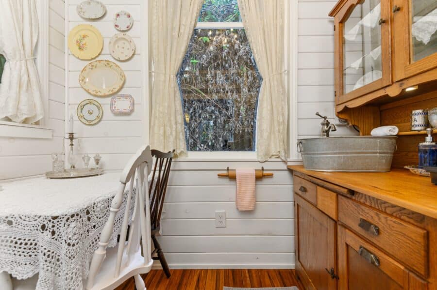 Lace-covered table, plate wall, and antique hutch inside the Cottage tiny house