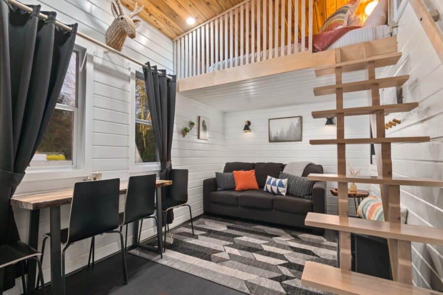 Living room of the Finlandia tiny house at Tiny Digs with a floating maple staircase and sofa