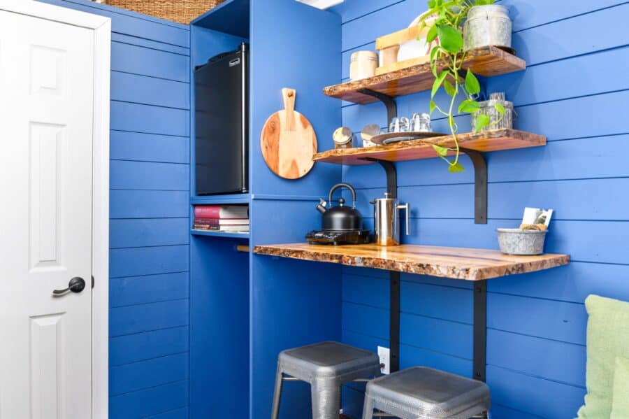 Live-edge wood shelves, kettle, and bar stools in the Merlot tiny house kitchenette
