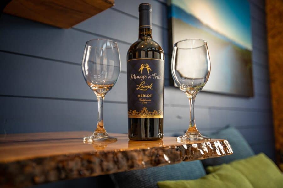 Wine bottle and two glasses on a live-edge counter inside the Merlot tiny house