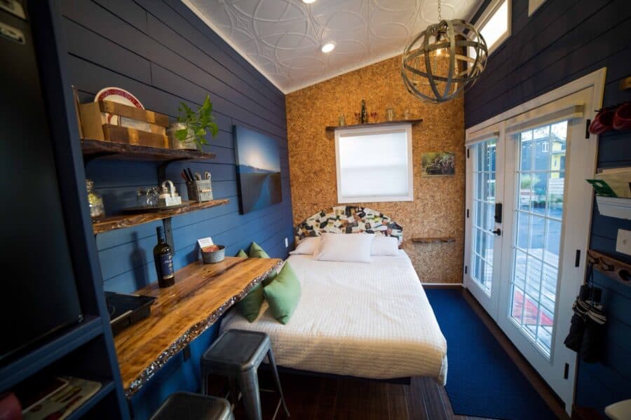Queen bed, cork wall, and live-edge desk inside the Merlot tiny house