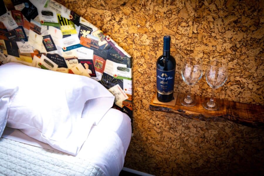 Wine label headboard and bedside shelf with wine glasses in the Merlot tiny house