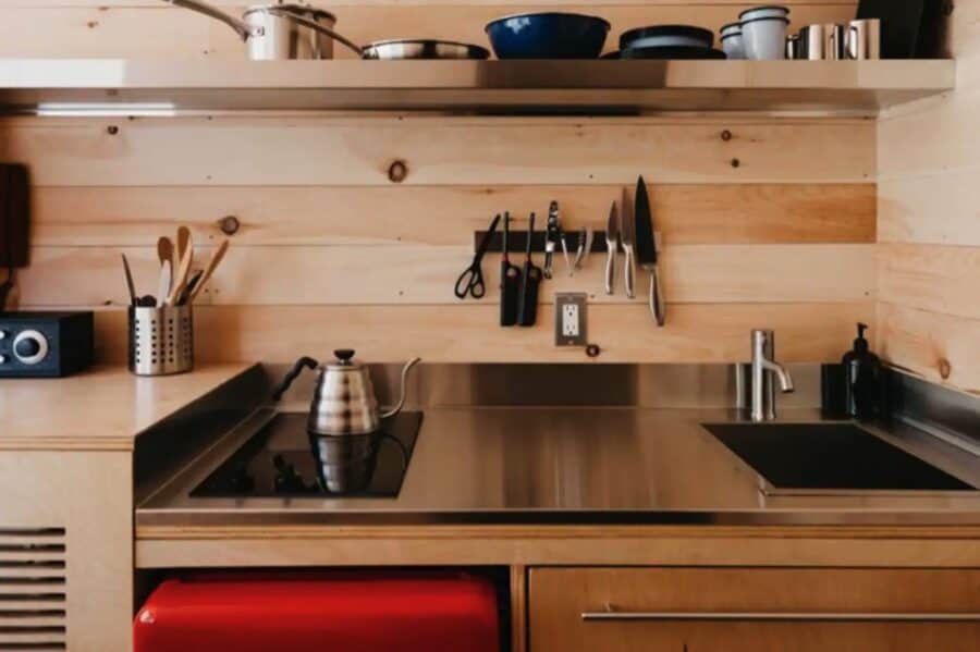Compact kitchen with modern appliances and wooden accents in a tiny getaway cabin.