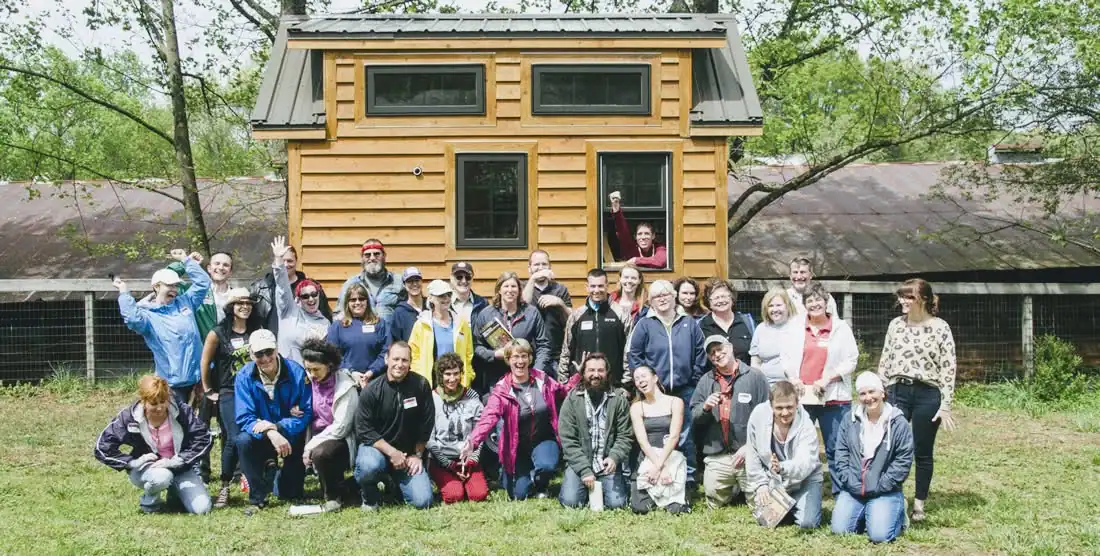 Group of people in front of a tiny house during building workshop.