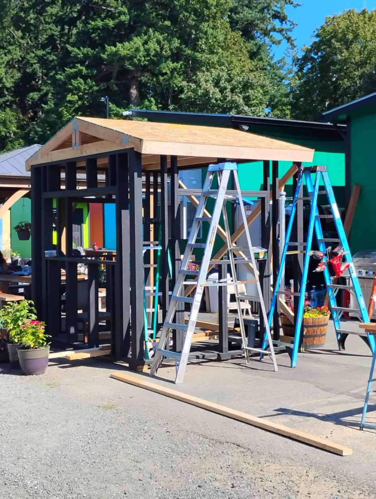 A new tiny home unit framed in black-painted lumber with a shed roof under construction at a Bellingham village