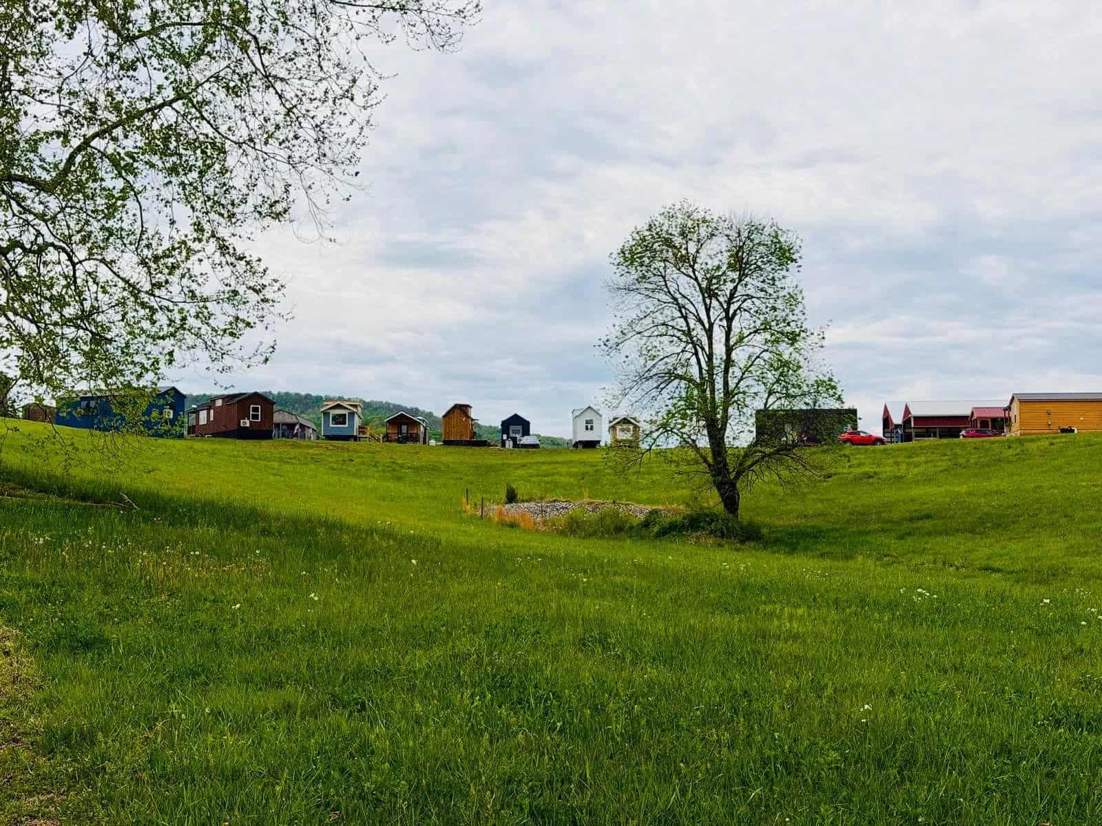 Variety of tiny house styles at Tiny Homes Village with a red-roofed community barn