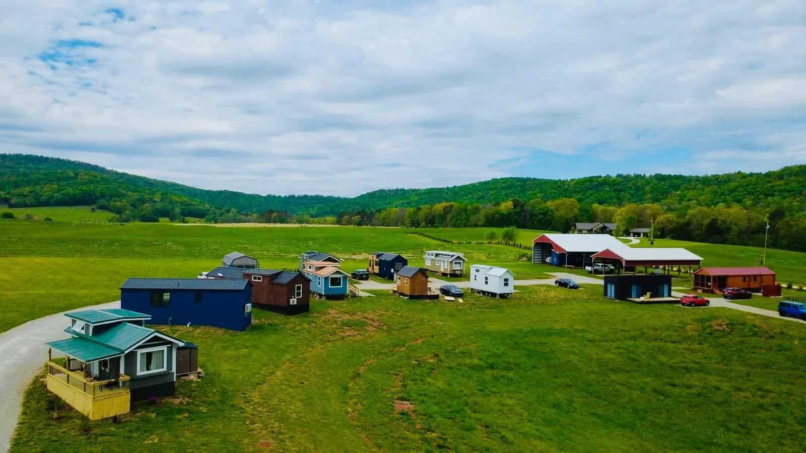 Colorful tiny homes spread across the green hillside at Tiny Homes Village in Tennessee