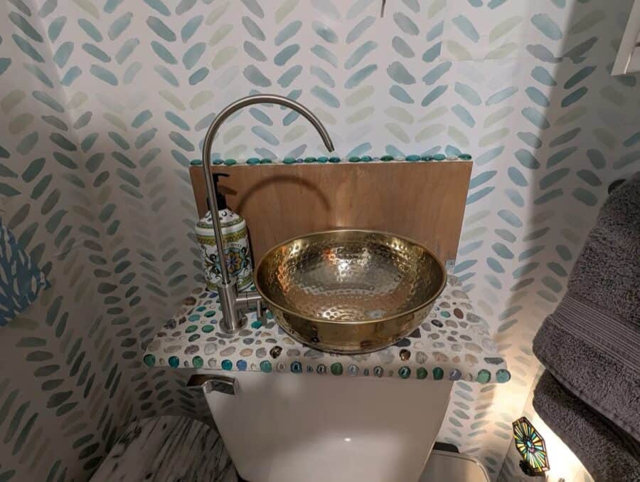 Compact bathroom sink with a gold basin and modern faucet in a tiny house.