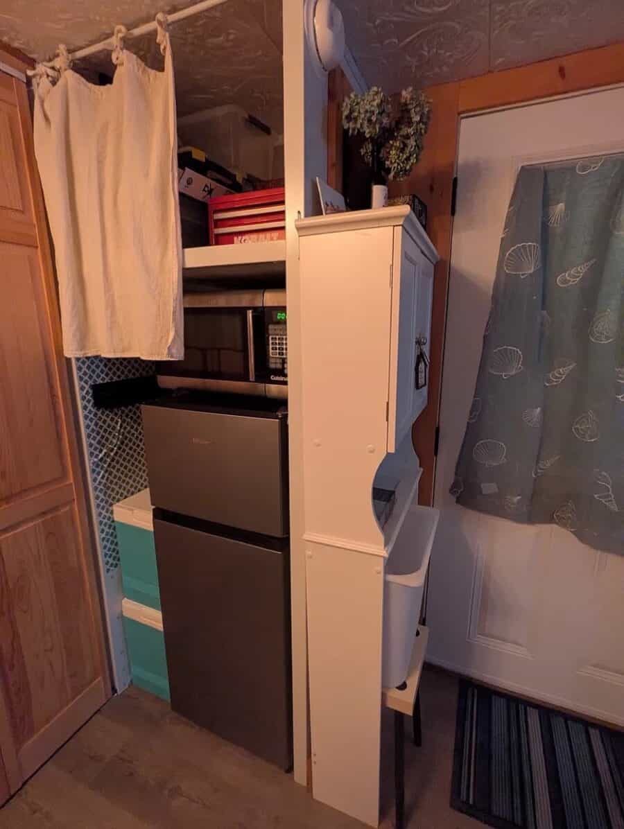 Compact kitchen with microwave, mini fridge, and storage in a tiny house rental.