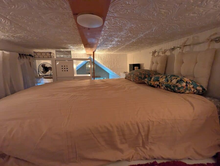 Compact tiny house bedroom with a large bed and soft bedding.